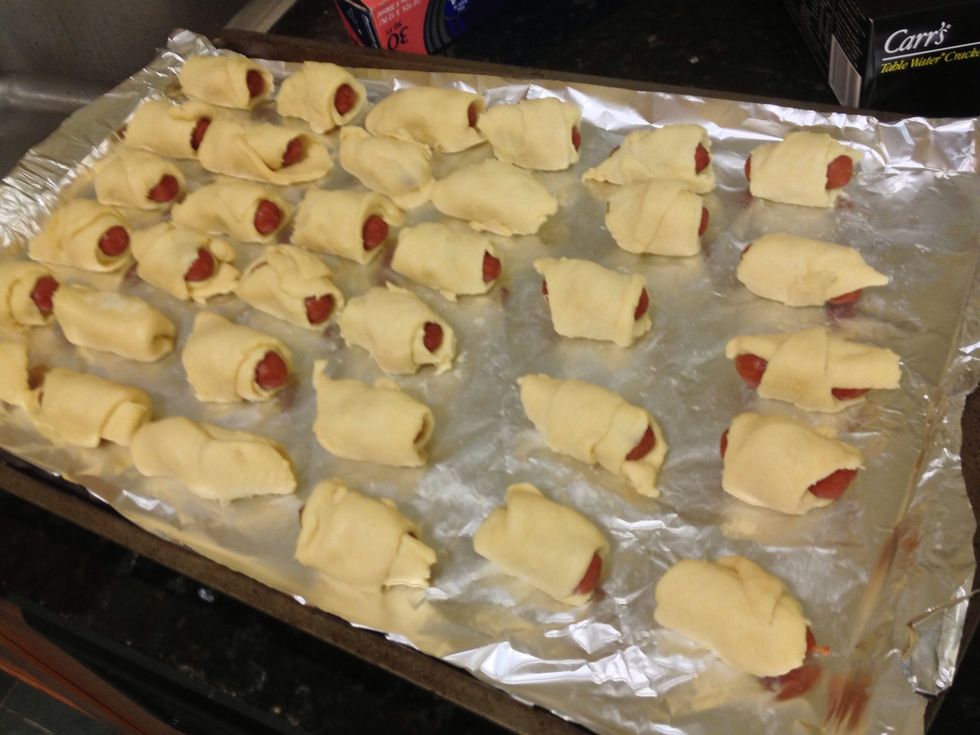 Cut each crescent dough into 2 or 3 triangular pieces. Wrap each hotdogs with dough. Doesn't need to be super pretty. Lightly grease the baking sheet.
