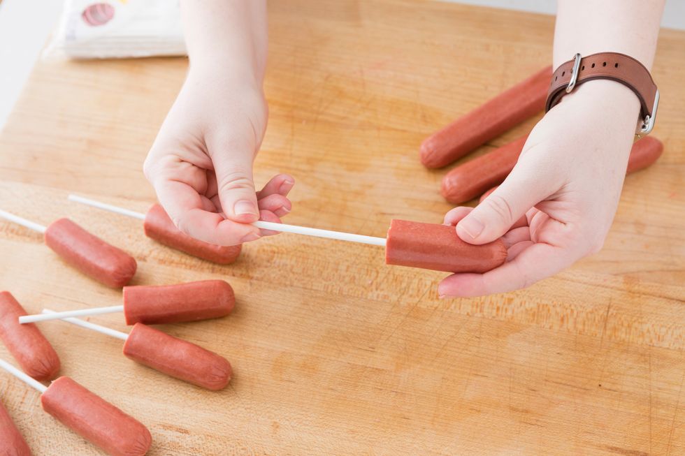 Cut each hot in half and then insert a lollipop stick in the end that has been cut. Make sure to dry off each hot dog with a paper towel so your cornmeal coating sticks.