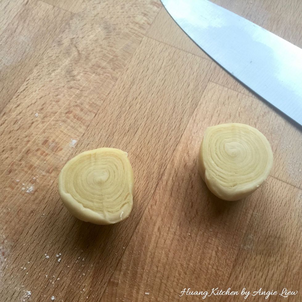 Cut each of the small rolled dough into two equal halves with a sharp knife. The circles can be clearly seen on each piece of the cut dough.