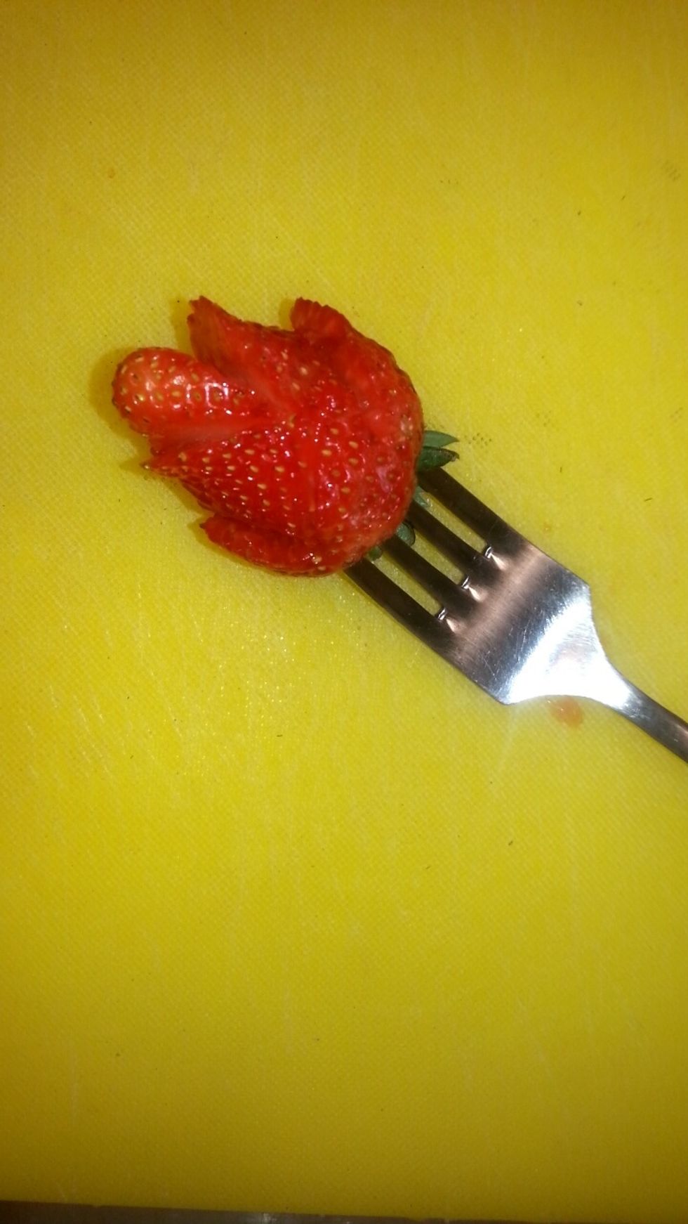 Cut flaps onto the bottom base of the strawberry with a paring knife, and push them outwards to give the illusion of petals.