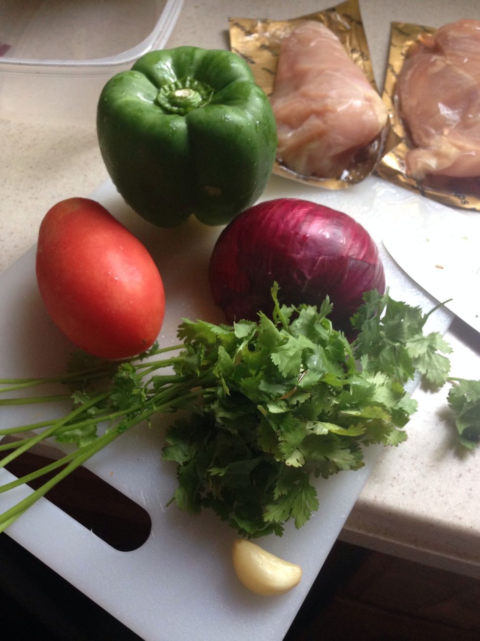 Cut half of your tomato, all your cilantro, and garlic. Cut 1/4 of your onions in small pieces.