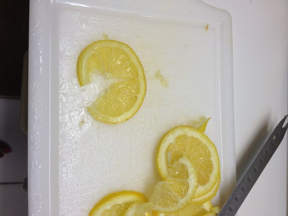 Cut lemon slice in half up to the inside of the rind. Repeat with rest of lemon slices.