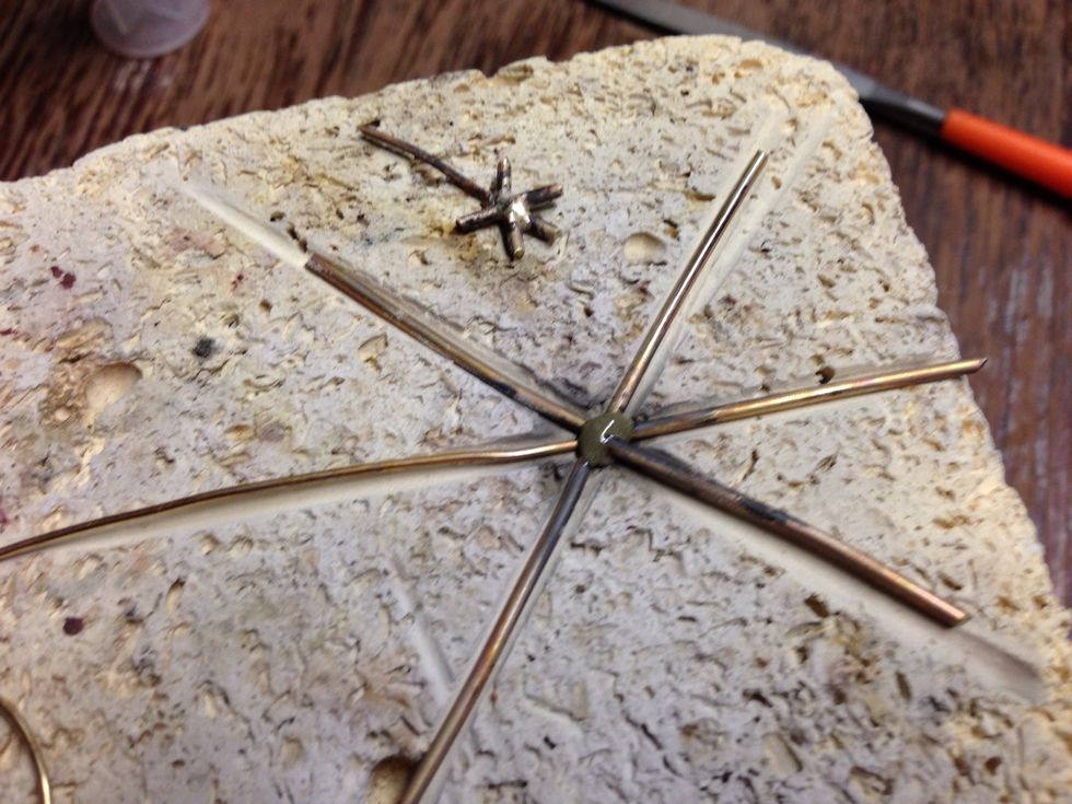 Cut off the spokes to the finished lengths: 5 thick = .25", 1 thin = .5"  lay the spokes back on the fire brick. Move each spoke into the center until they touch, and repeat from step 3.