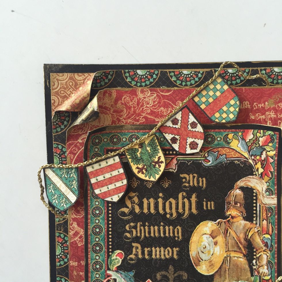 Cut out 5 flags from backside of Exquisite Epoch. Use foam adhesive to adhere in a curve to top left corner, like pictured. Glue gold string to top edge of banner.