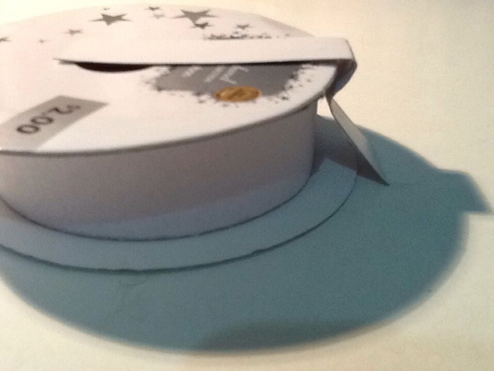 Cut out a rectangle of white cardboard and fold it along the sides of the spool. This will act as a hinge for the opening and closing of the lid.