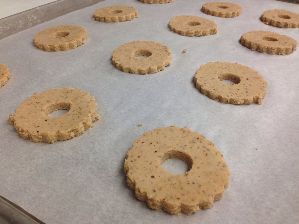 Cut out Linzer shaped cookies and place on a parchment lined sheet tray.