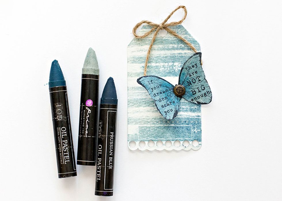 Cut out the butterfly and add to the tag. Adhere a metal embellishment to the center of the butterfly. Tie the string that comes with the tags in a bow, and add to the top to finish off the tag.