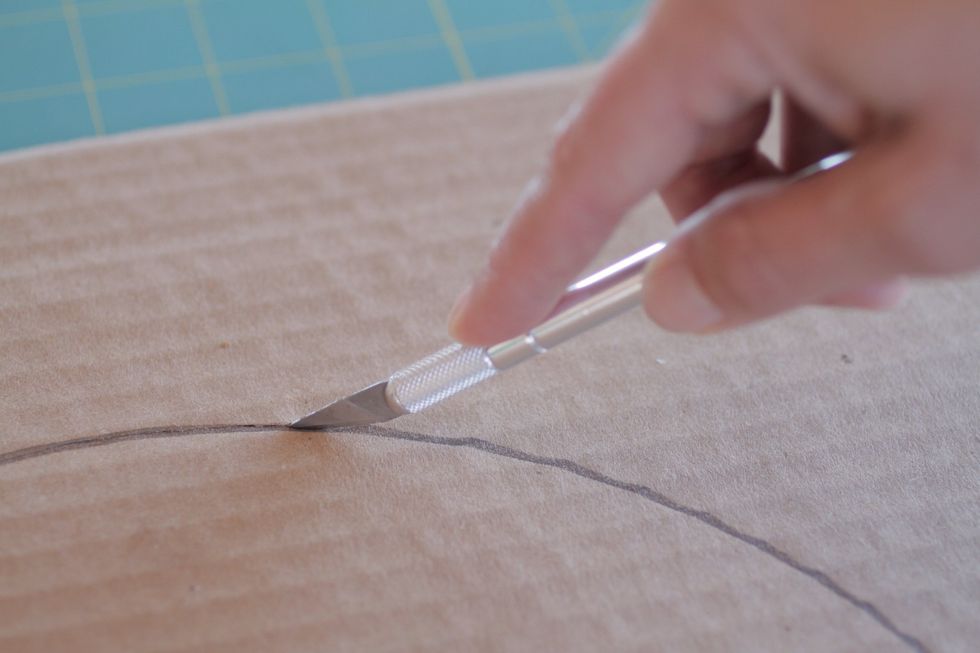 Cut out the larger circle with the exacto knife or scissors. Be sure to protect whatever surface you are working on.
