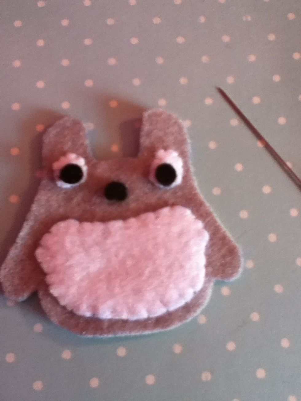 Cut out three circles out of black thread and also sew them on using a fell stitch