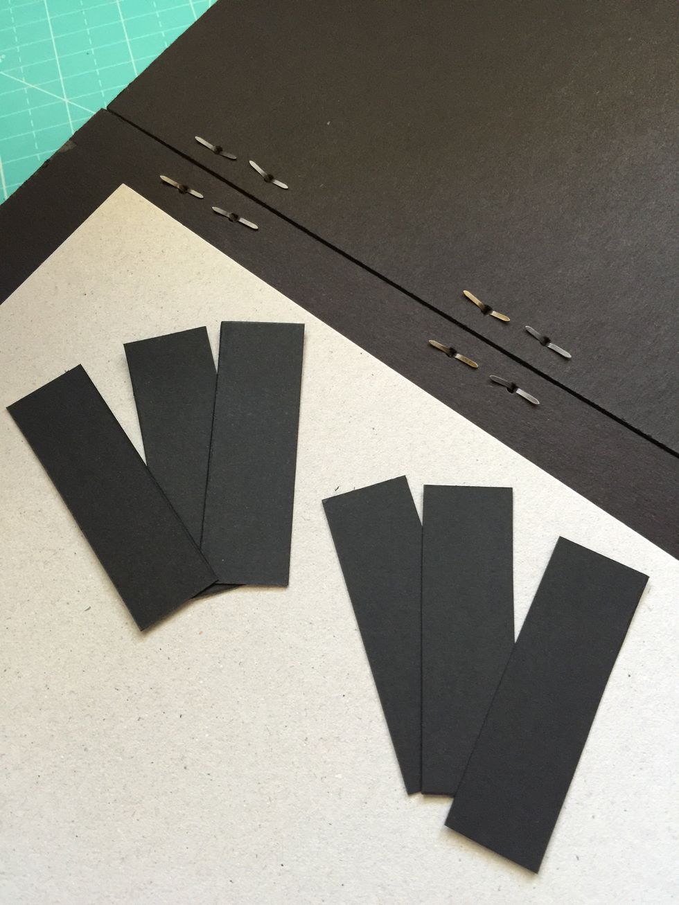 Cut six small pieces of black cardboard that will cover the back of the brads.