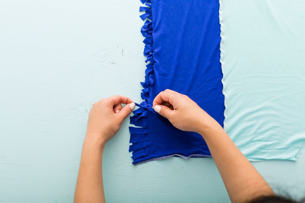 Cut slits from the bottom of the shirt to the line marking the bottom of the bag. Cut both the front and back layers together so that the fringes line up. Cut slits at least one inch apart.