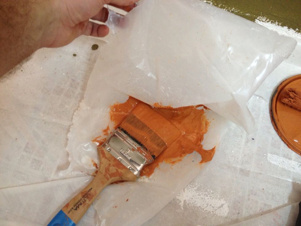 Cut some clean plastic off from the edge of the drop tarp. Put the paint brush or roller in the plastic.