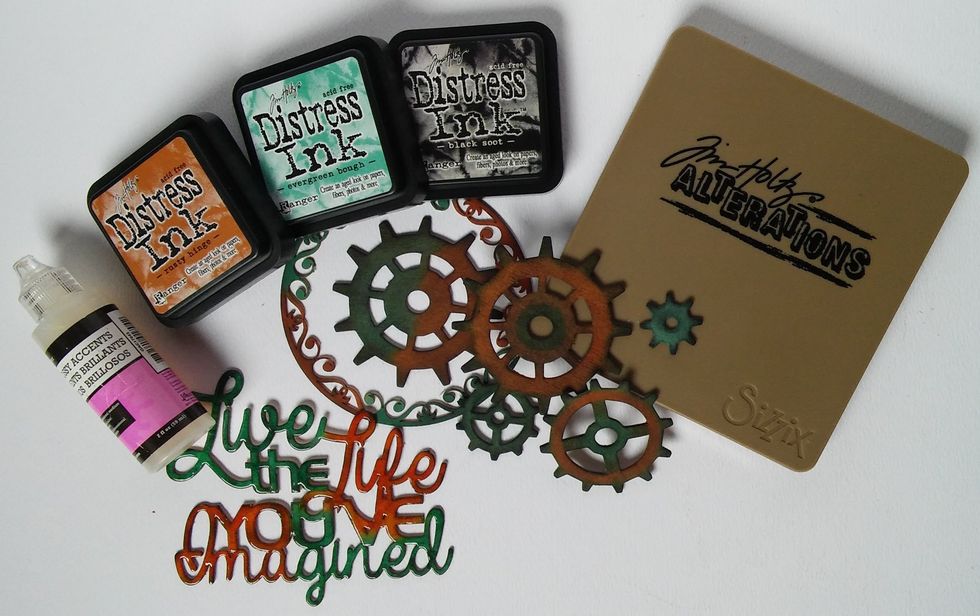 Cut some gears from chipboard using the Tim Holtz Gadget Gears Die. Ink the gears, flourish circle and the phrase with your distress inks. Add glossy accents to the phrase and leave to dry.
