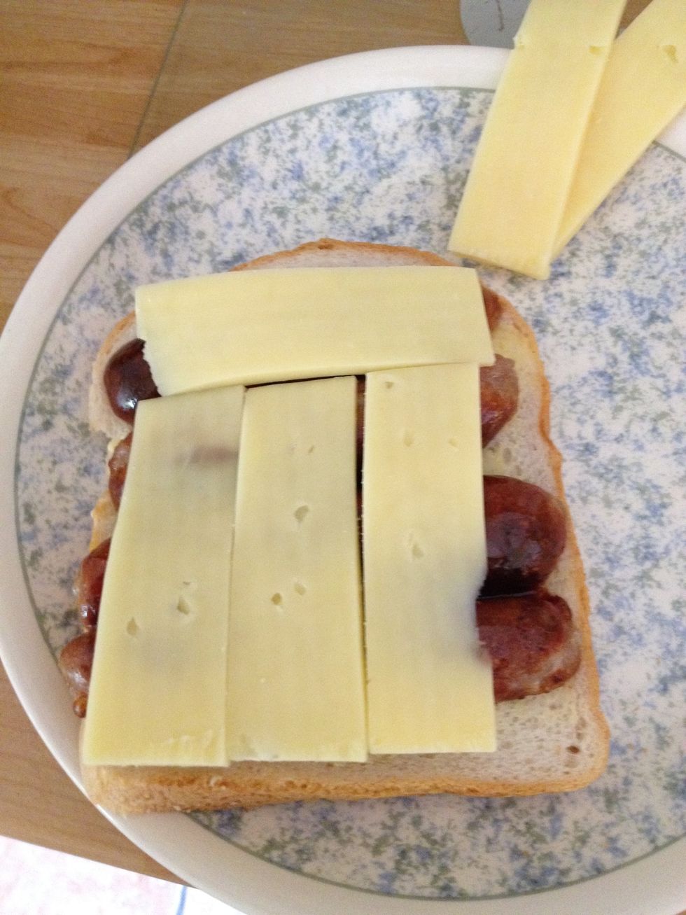 Cut some slices of cheese and lay them over the sausages. Add some sauce if you desire. I put some garlic mayo on at this point but you could add ketchup or some chilli sauce