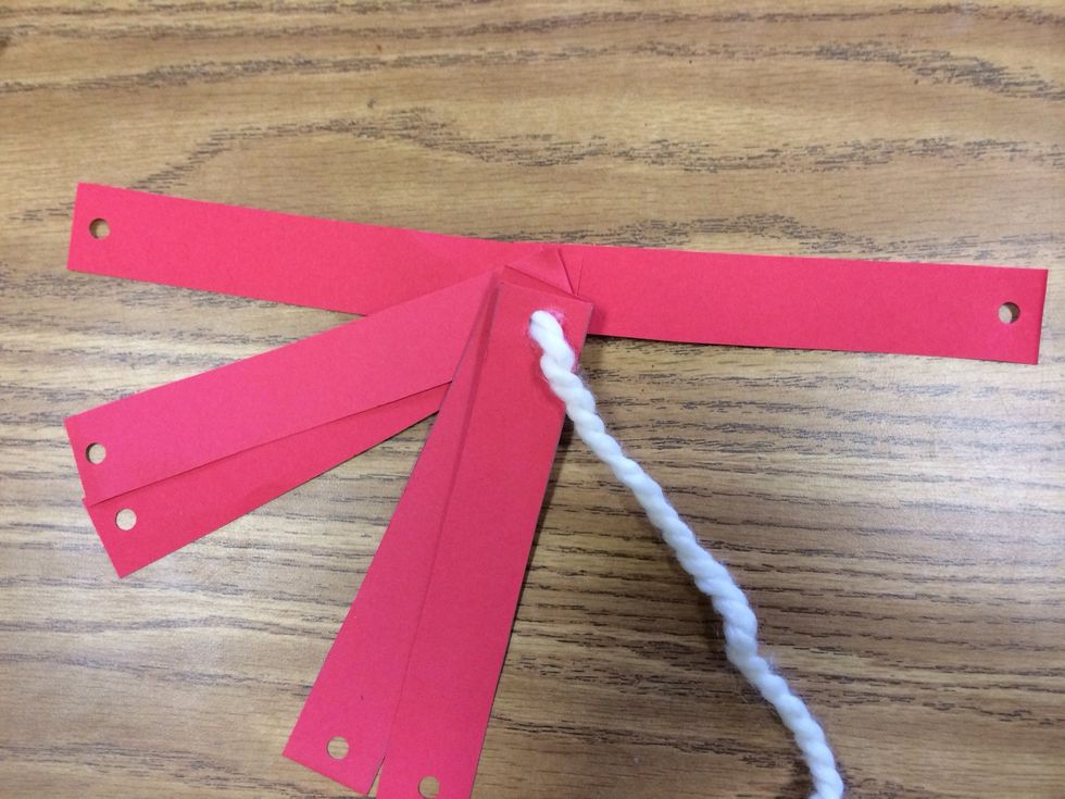 Cut string to desired length. Tie a knot at one end. To make lacing easier wrap a small piece of scotch tape around the other end. Line up all of strips and lace the string through the holes.