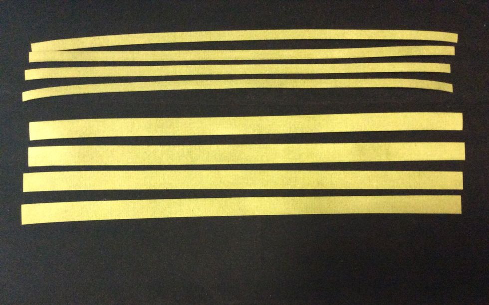 Cut strips of grunge paper at 1/2 and 1/4 inch widths, 4 of each width and ink with distress ink. heat or air dry before use. Apply score tape to back of strips.