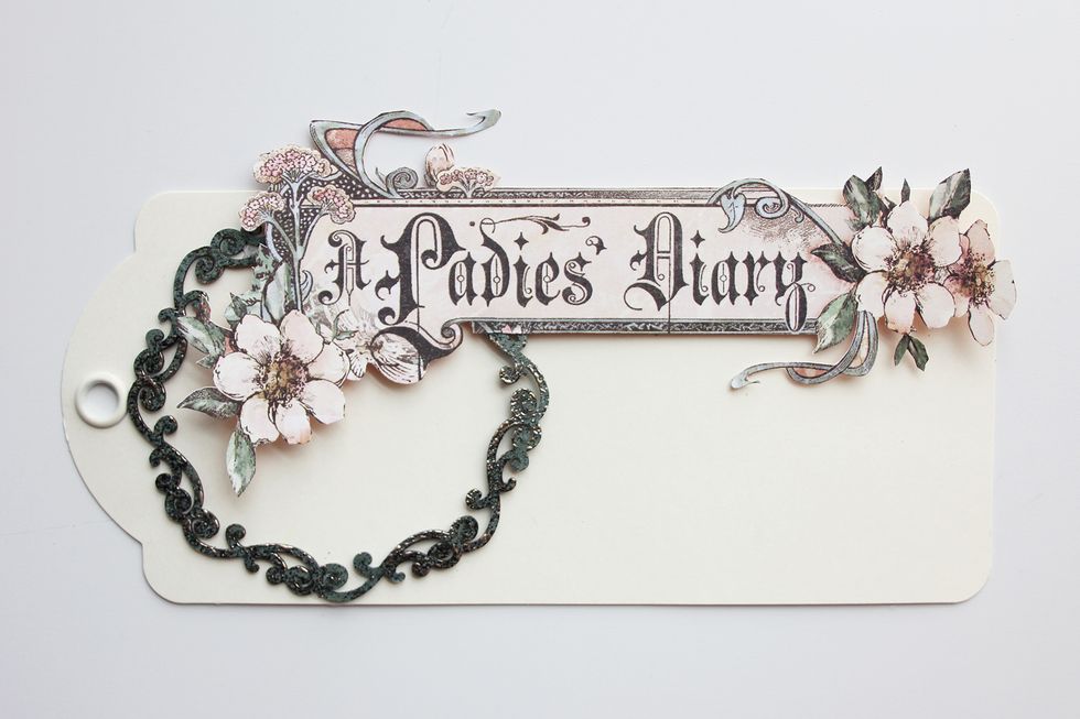 Cut the "A Ladies' Diary" image and apply to the top of the tag using dimensional foam adhesive.