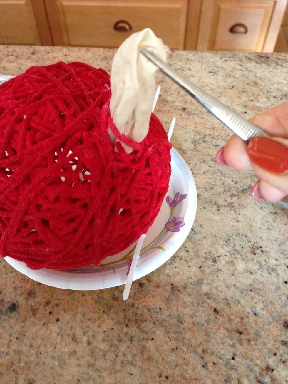 Cut the balloon at the tie and pull out with tweezers