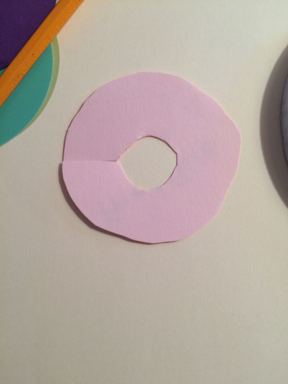 Cut the edges of the circle so that they are curvy and wavy, like the frosting on a donut would be, and add a hole in the center.