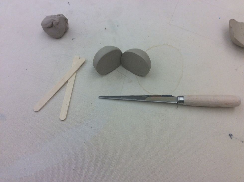 Cut the larger ball of clay in half.