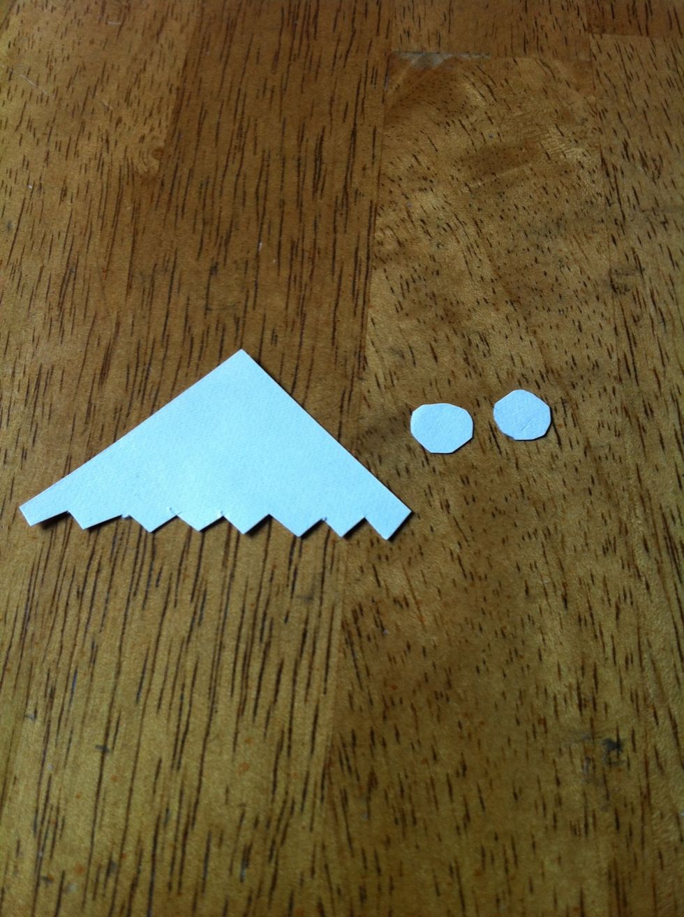 Cut the longer edge of the triangle (The triangle you cut out earlier) to look like teeth. Also cut out two circles for the eyes.