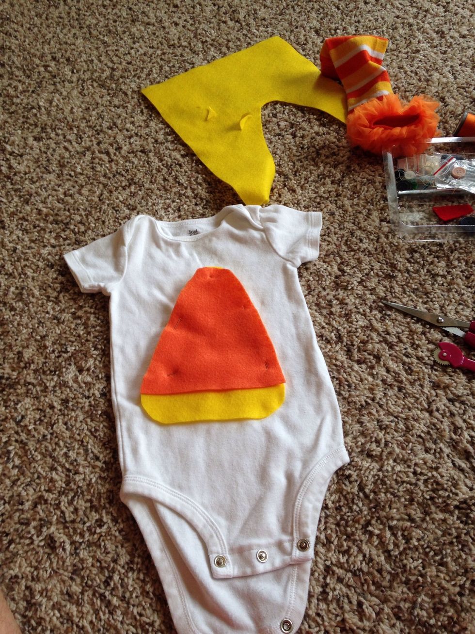 Cut the orange felt a little smaller than the yellow (as shown in picture) pin them to the onesie