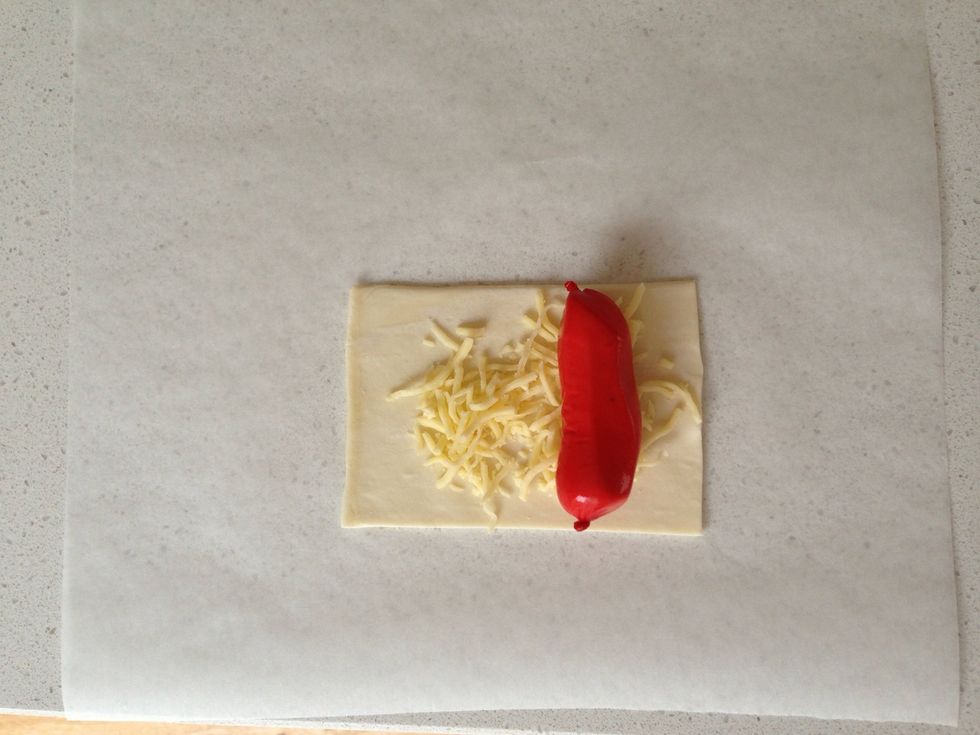 Cut the puff pastry into rectangle. You can spread dijon mustard for a spicy kick. Position the sausage in one edge sprinkle with cheese.