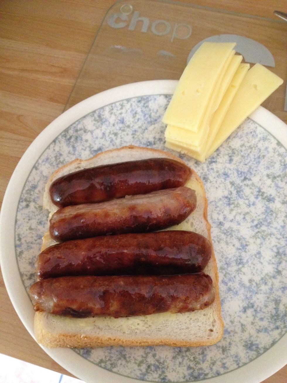 Cut the sausages in half down the middle like you are opening up a camel to sleep in for the night because you got stranded in a desert. Place the open sausages face down on the bread.