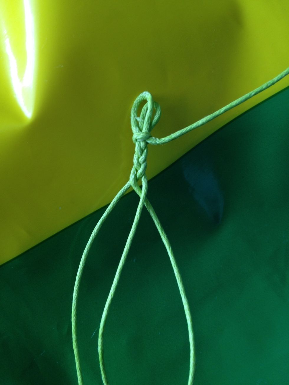 Cut the short string and start braiding the 3 longer strands like so.
