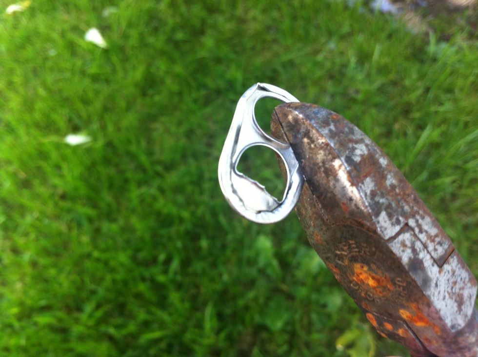 Cut the tab as indicated in this image. In the wild you'll just have to improvise a tool such as stone. Or just bend it back and forth till it breaks apart.