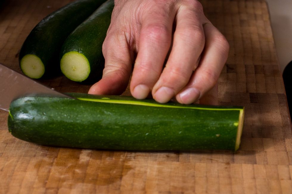 Cut the tips and tails off your zucchini and then half them.