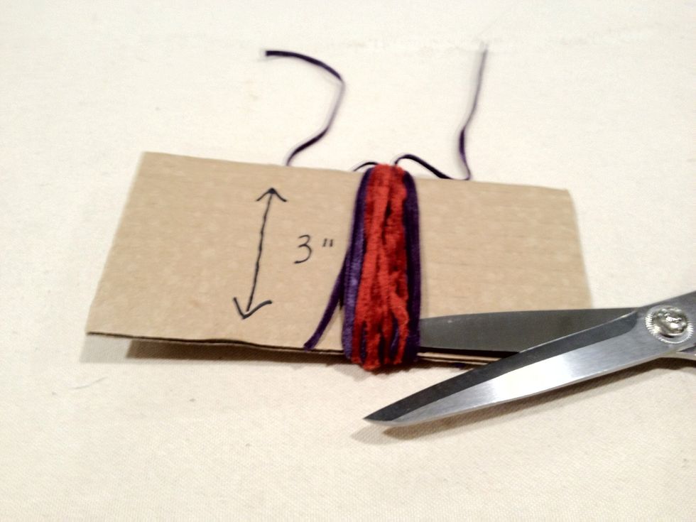 Cut the yarn across the bottom of the cardboard.