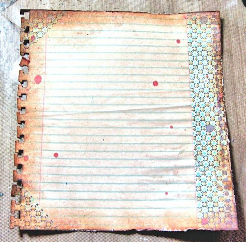 Cut this 6" panel from  7 Gypsies Ordre du Jour Seize the Day paper. Use a notebook punch on one side.  Ink and heavily distress the edges. Spatter with Pink Poodle Glimmer Mist.