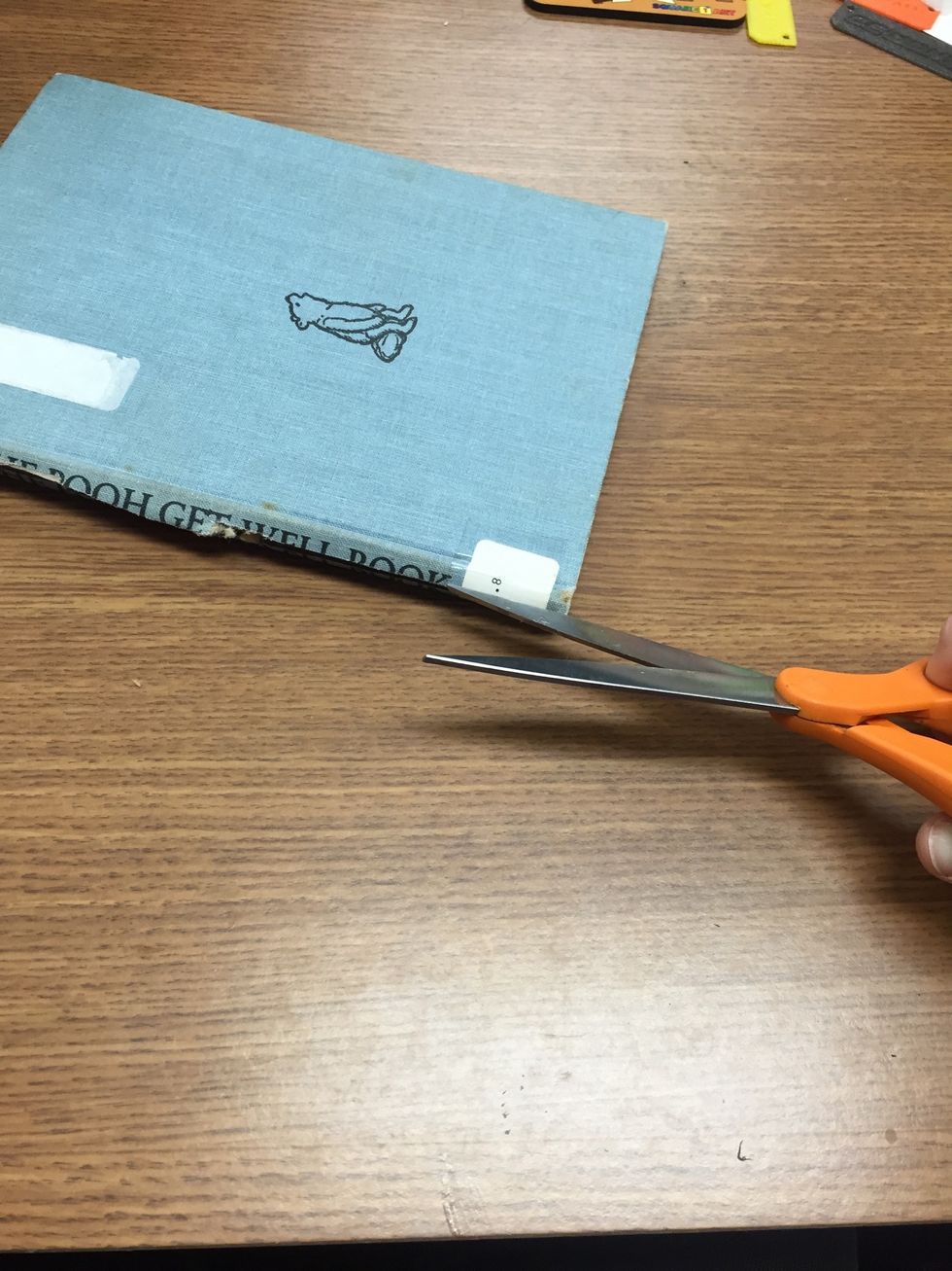 Cut through the spine of the book. Be careful!