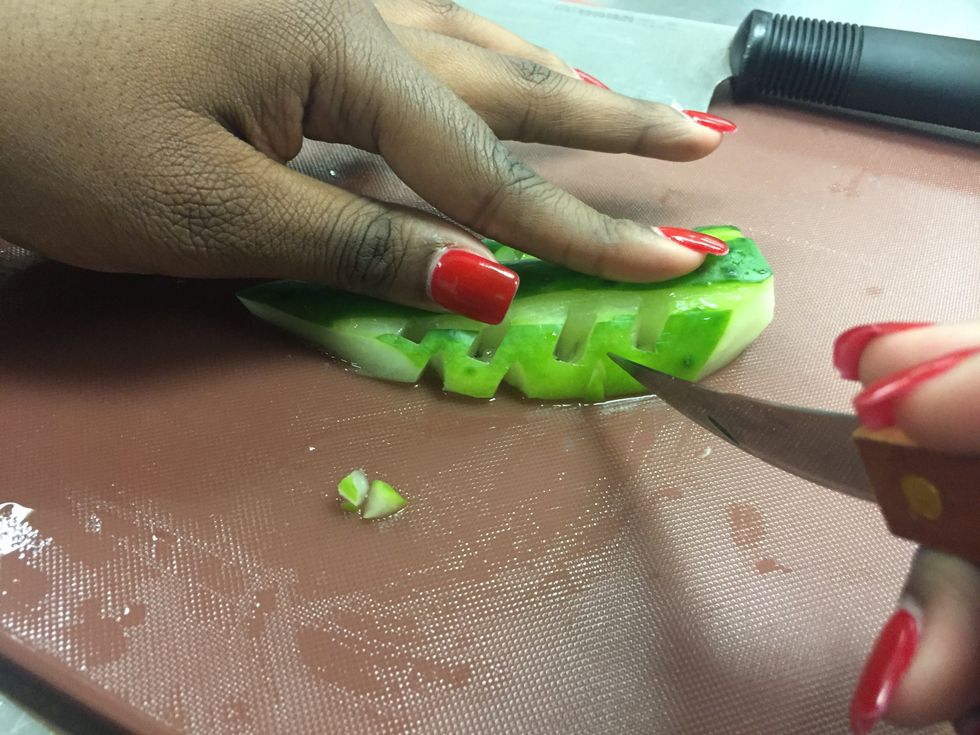 Cut tiny triangles down both sides of the cucumber.