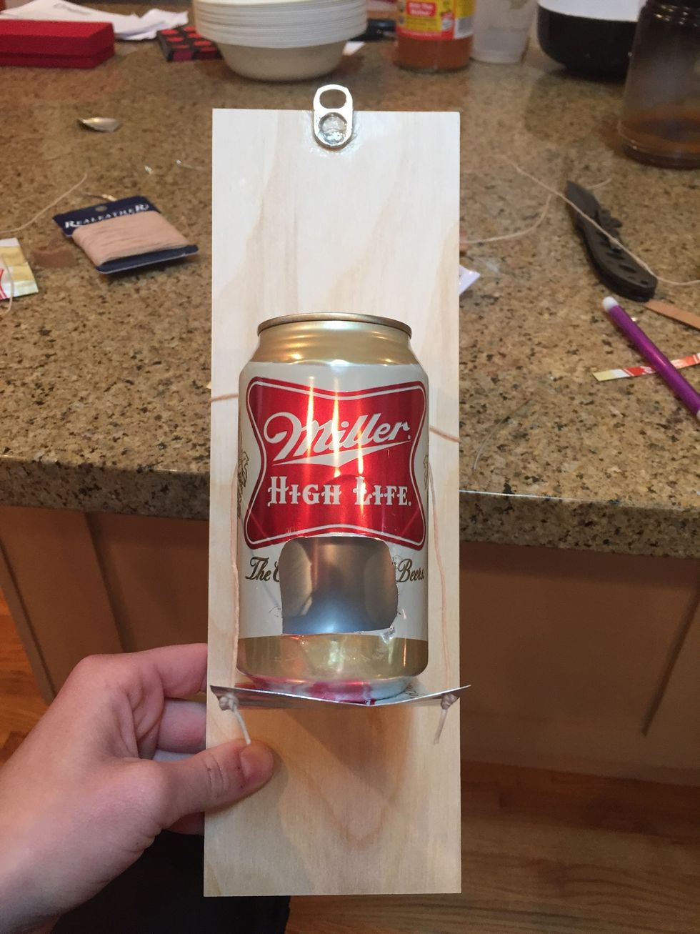 Cut two holes into the end of the can strip and stick string through the hole and tie knots at the bottom