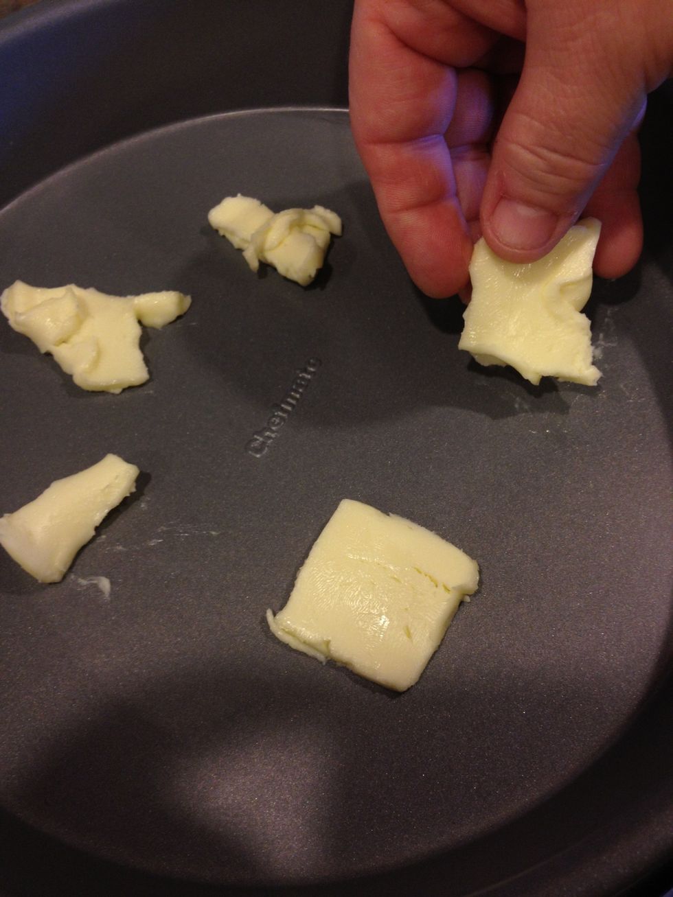 Cut up several tabs of butter and place them evenly at the bottom of your pan.