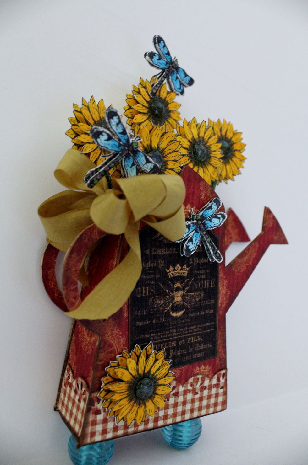 Cut Water Can out from chipboard and Sizzix Die...cover with French Country Paper. Add Sunflowers and Dragonflies to Can. Add a pretty bow. Place watering can on beads.