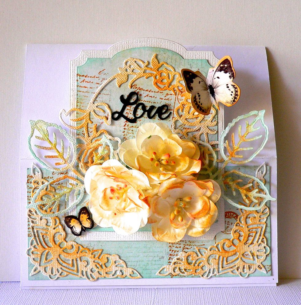 Cut word die "LOVE" with die cut and adhere to front of card. Adhere butterflies and inked coloured Magnolia flowers with foam tape.