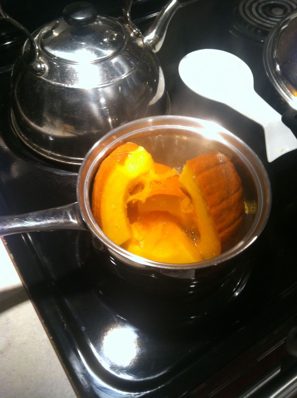 Cut your pumpkin in half, scoop out the seeds from one of the halves, and cut into quarters. Cover a pan with water and start steaming your pumpkin.