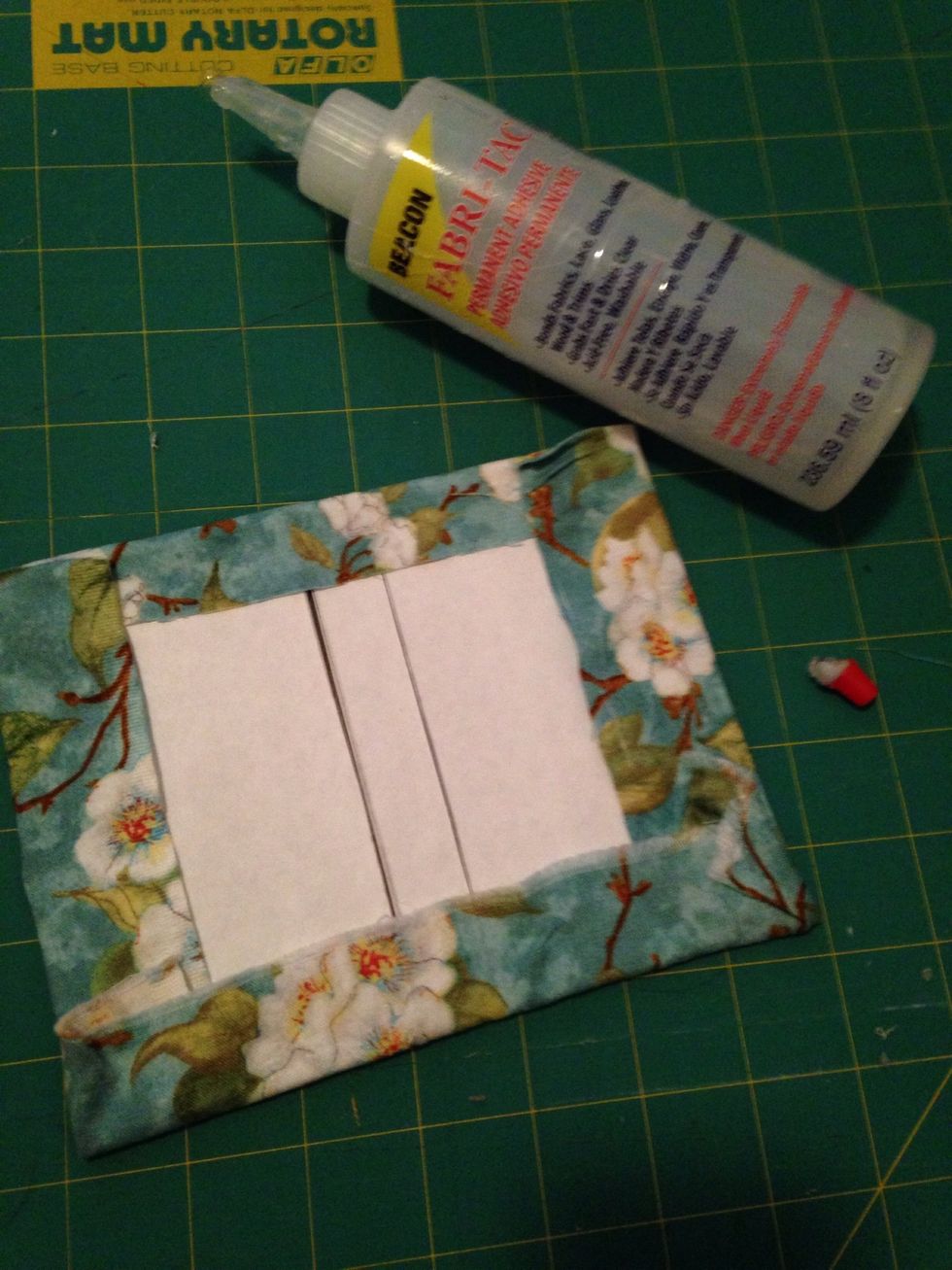 Dab the inside border of the cover with glue and wrap the fabric around it. It should stick well.