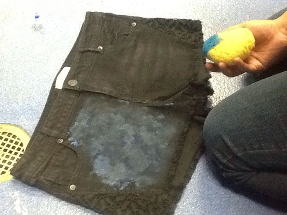 Dab your first paint onto the denim with sponge.