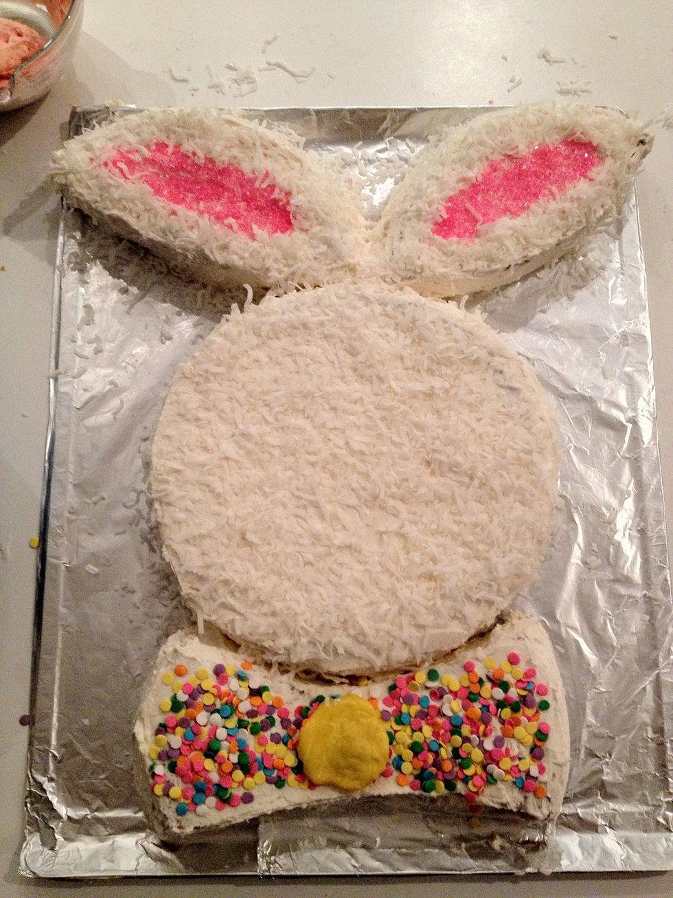 Decorate as desired! I chose to cover the face and ears with coconut, use pink sugar crystals in the ears, and cover the bow tie with confetti sprinkles. Don't mind the yellow blob on the bow tie!