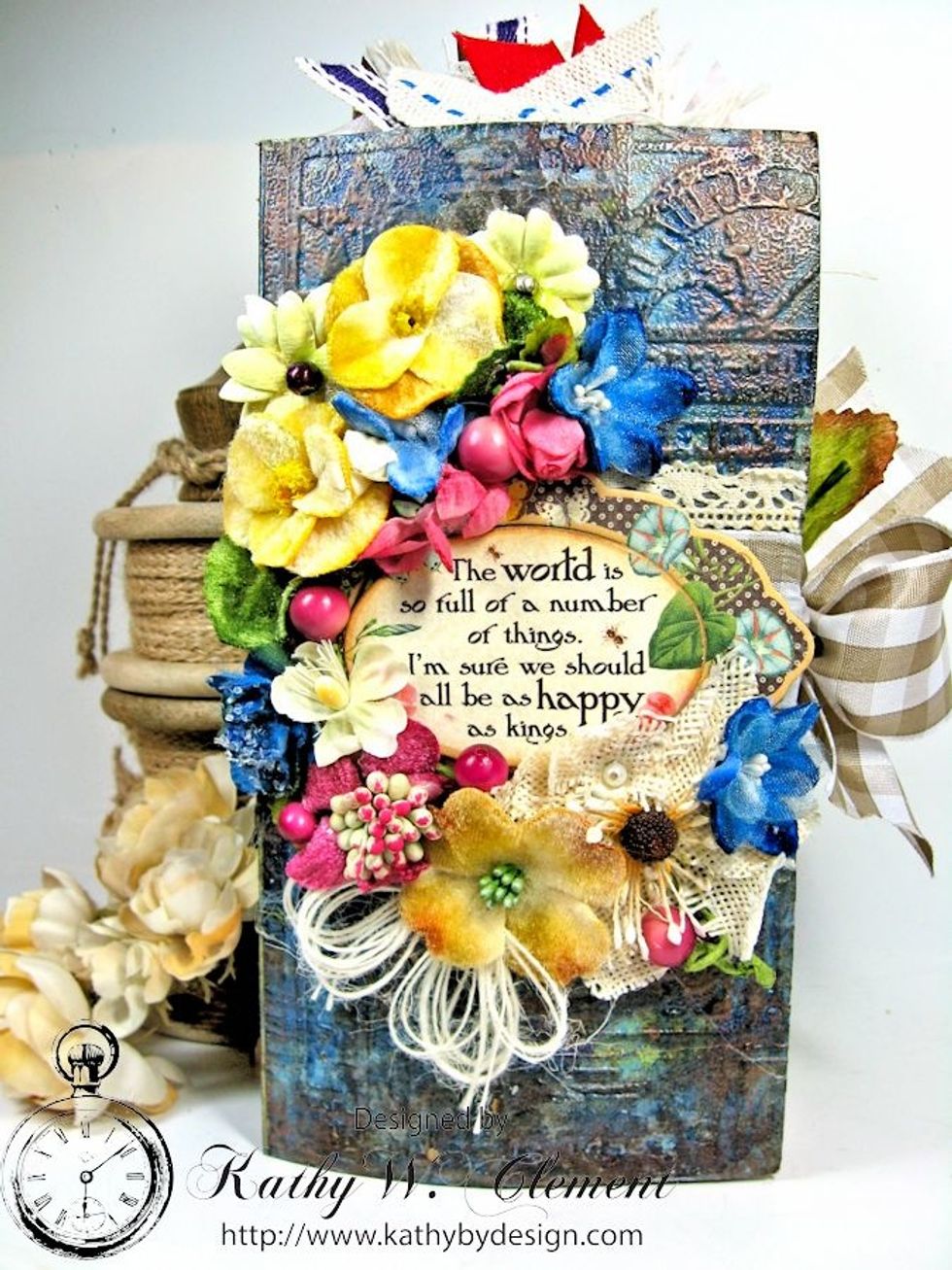 Decorate the cover with chipboard medallion, securing with foam tape.  Add Petaloo flowers and burlap string bow.