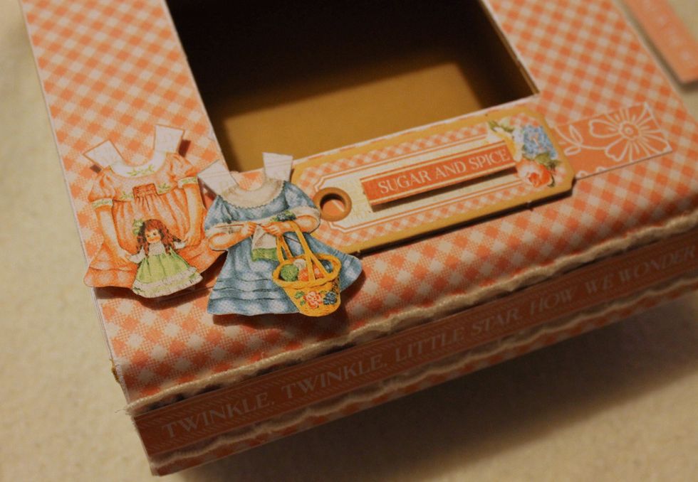 Decorate the downside of the box with two cut out dresses, a border, a chipboard piece and a cut out text.