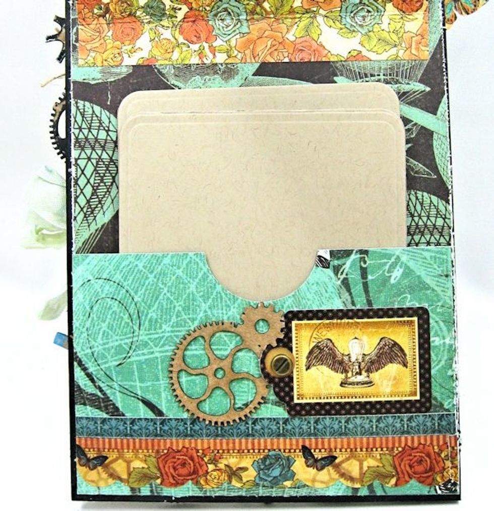 Decorate with border sticker, border tag, brad & unpainted gear chips.  Cut photo mounts and tuck into the pocket. Flip the tag over.  NOW you may glue the front panel onto the tag.  Hooray!