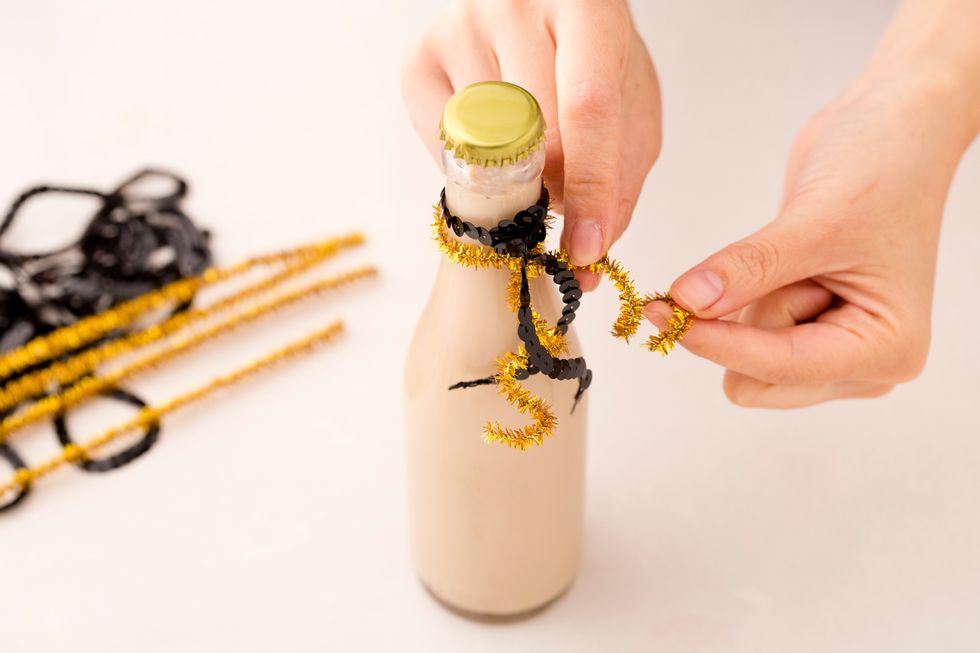 Decorate your bottle to give the cocktail an extra fancy touch. We tied gold pipe cleaner and black sequin ribbon around the top. But feel free to experiment!