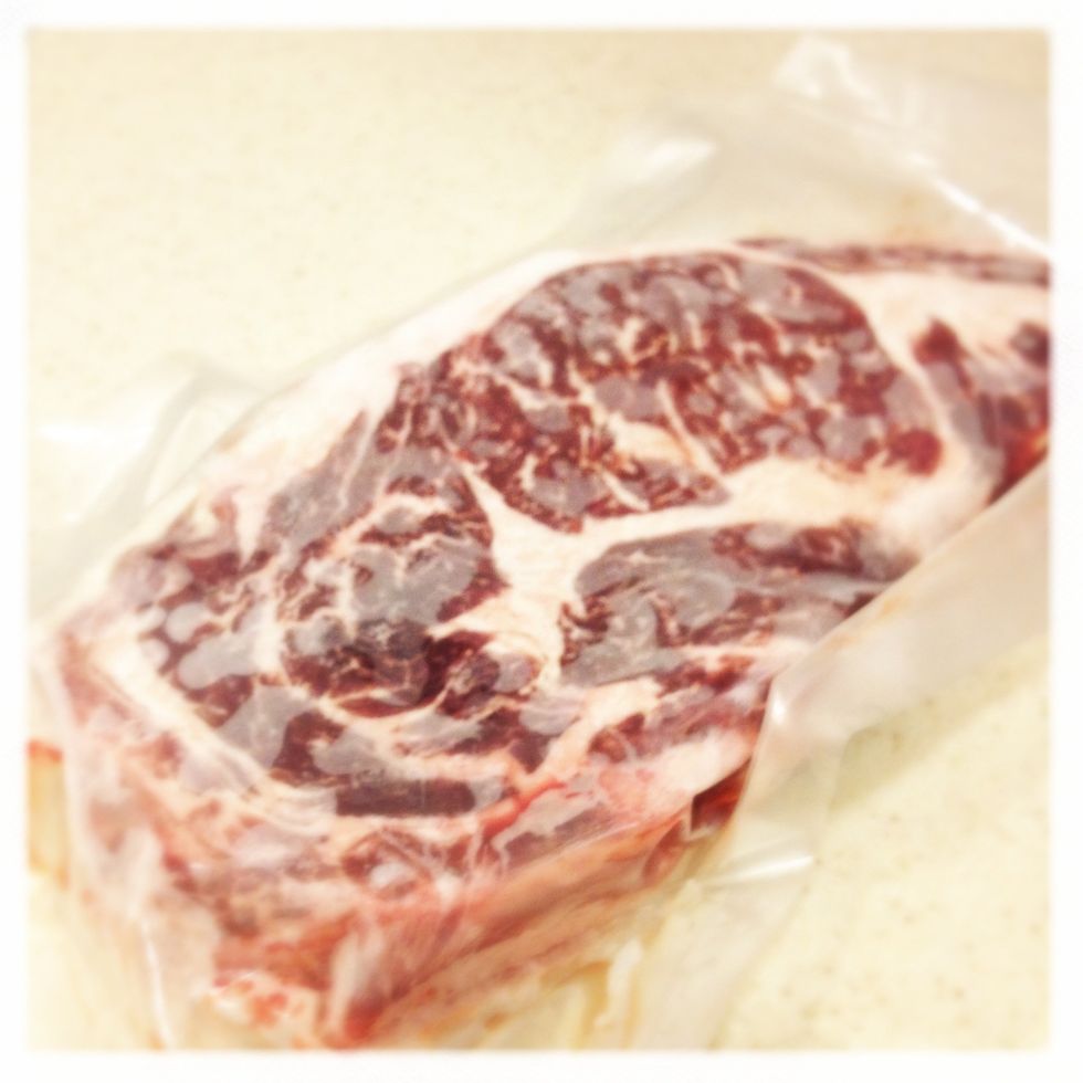 Defrost a frozen ribeye steak in its package from freezer to refrigerator for over night