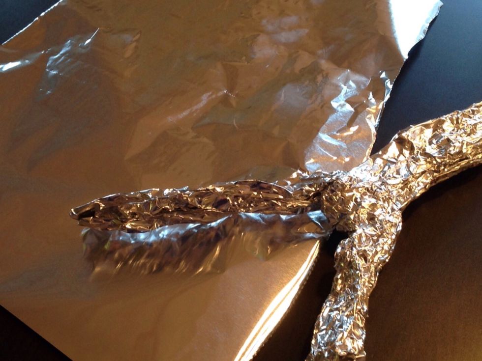 Den ena biten blir figurens b\u00e5da ben och den andra biten pressar du ihop s\u00e5 att det blir figurens kropp. Nu beh\u00f6ver du en ny bit folie till armarna inte riktigt s\u00e5 stor som de f\u00f6rsta bitarna.