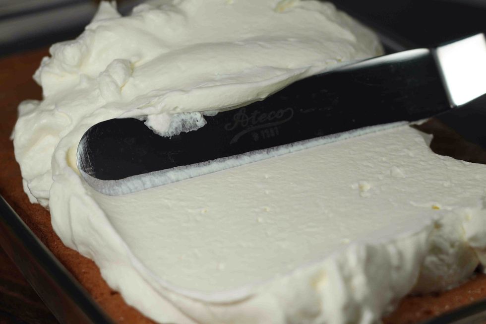 Despues de una hora, saque el pastel de el refrigerador y ponga el cool-whip encima del pastel.